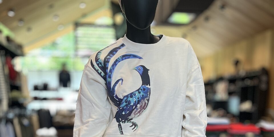 Mannequin in a cream sweatshirt with a blue bird graphic and denim jeans. © Sport Kessler GmbH