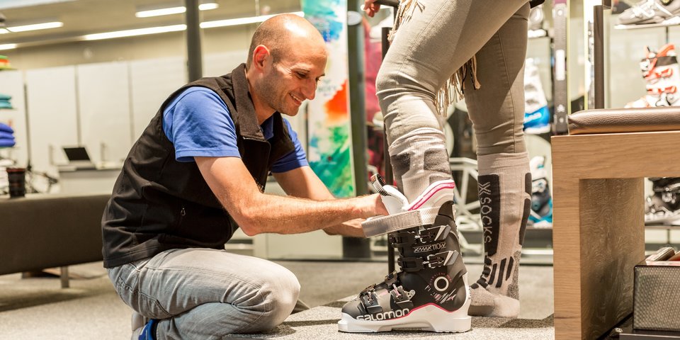A shop assistant helps a customer try on a ski boot. © Sport Kessler GmbH